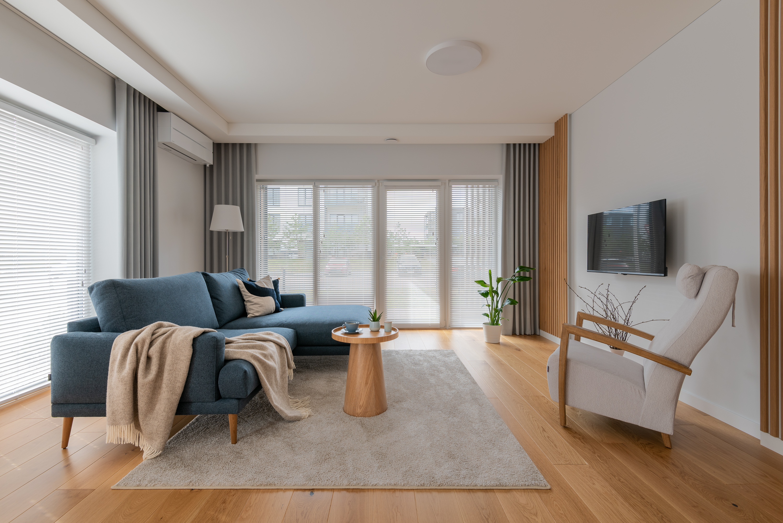 A serene bedroom scene featuring a bed with light brown sheets and pillows against a cream-colored wall.